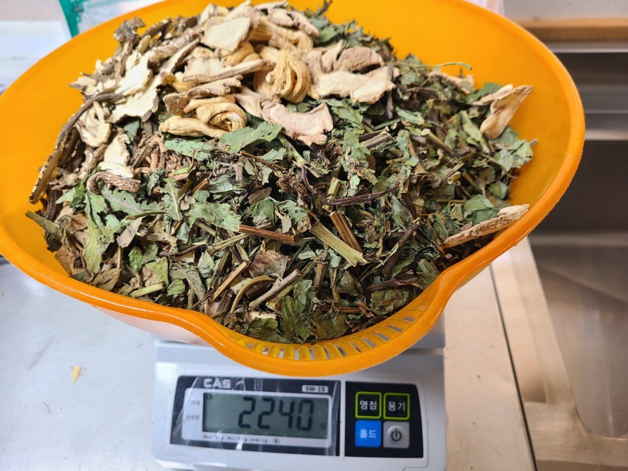 저울로 한약초를 계량하는 모습